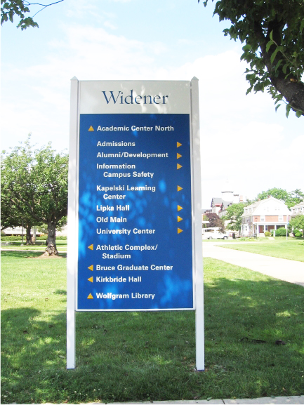 A tall panel sign, surrounded by a beautiful garden