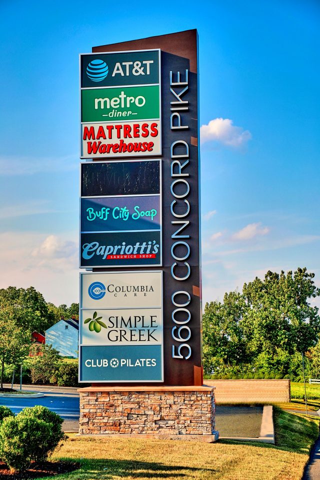 A pylon sign made by HES signs, fitted with various business signs, placed on a brick foundation.